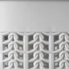 A close-up view of the top section of a white laundry basket with a textured lid and a decorative woven pattern below. Produktbild-Vorschau