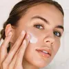 A woman is applying cream to her face. Náhľad obrázku produktu