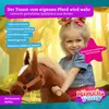 A young girl is riding a brown plush horse with a colorful background. Produktbild-Vorschau