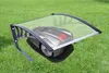 A robotic lawnmower is parked under a transparent canopy on a green lawn. Podgląd zdjęcia produktu