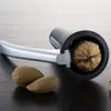 A nutcracker with a walnut inside and two almonds next to it, on a dark wooden surface. Produktbild-Vorschau