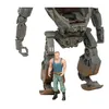 A small figurine of a man stands in front of a large, gray mechanical suit. Náhled obrázku produktu