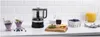 A black KitchenAid mini food processor is displayed on a kitchen counter with blueberries, orange slices, juice, and desserts. Náhľad obrázku produktu
