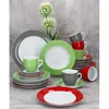A collection of dinnerware, including plates and cups, arranged on a surface with a wooden-like backdrop and decorative floral elements. Produktbild-Vorschau