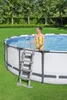 A woman in a yellow swimsuit is standing in an above-ground swimming pool, holding onto the ladder. Anteprima dell’immagine prodotto