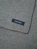 A close-up view of a gray knitted scarf with a dark blue label. Anteprima dell’immagine prodotto