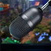 A close-up shot of a black Razer Seiren Mini microphone with a silver band and a green indicator light, set against a blurred background that appears to be a video game scene. Podgląd zdjęcia produktu