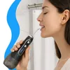 A woman is using a black and gray water flosser in a bathroom. Voir les images du produit