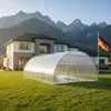 A large, modern house with a swimming pool enclosure in the yard, set against a mountainous backdrop. Produktbild-Vorschau
