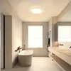 A modern, minimalist bathroom with a freestanding bathtub, double vanity, and a ceiling light. Produktbild-Vorschau