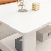 A close-up view of a white coffee table with decorative items and storage boxes. Produktbild-Vorschau