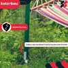 A green metal post with a hammock attached, set in a garden with lush green foliage. There are marketing overlays indicating product features. Náhľad obrázku produktu
