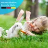 A young girl and a rabbit lying on grass, both eating carrots. Produktbild-Vorschau