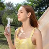 A young woman using a handheld fan outdoors. Produktbild-Vorschau