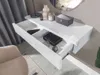 A close-up view of a white, glossy console table with an open drawer, revealing various items inside. Produktbild-Vorschau