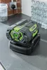 A battery charger sits on a countertop next to a wall outlet and a stack of water bottles. Produktbild-Vorschau