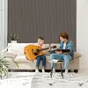 A father and son are sitting on a couch, with the son playing the guitar and the father looking at a book. Produktbild-Vorschau