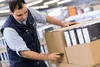 A warehouse worker is scanning a box of binders with a handheld scanner. Produktbild-Vorschau