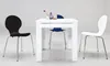 A white dining table with three chairs (one black, one white, one blue) around it. There are decorative items on the table. Produktbild-Vorschau