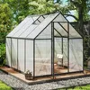 A greenhouse in a garden setting, with a table and chairs inside. Voir les images du produit