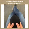 A person is holding a black sock, with their legs crossed in blue jeans in the background. Produktbild-Vorschau