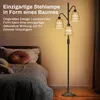 A floor lamp with multiple shades is placed next to a bed in a bedroom. Náhľad obrázku produktu