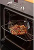 A glass baking dish filled with food is placed inside an open oven on a rack. Anteprima dell’immagine prodotto