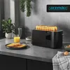A black toaster with toast in it, placed on a kitchen counter next to a glass of orange juice and a plate of toast. Náhľad obrázku produktu