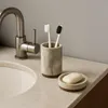 A bathroom sink area with a faucet, toothbrush holder with toothbrushes, and a soap dish with soap. Produktbild-Vorschau
