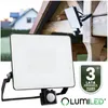 A floodlight with a motion sensor is mounted on a wooden structure, with a house in the background. A warranty badge is also visible. Náhled obrázku produktu