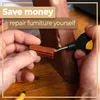 Hands repairing a wooden furniture leg with a repair tool and wax. Voir les images du produit