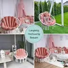 A collage of four images showing pink shell-shaped cushions for hanging chairs, some with children and in different settings. Produktbild-Vorschau