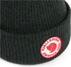 A close-up view of a knitted hat with a circular logo patch. Anteprima dell’immagine prodotto