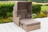 A multi-functional outdoor lounge bank with a canopy is set up on a paved patio next to a garden with flowers and greenery. Produktbild-Vorschau