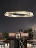 A modern dining room with a round table and chairs, illuminated by a large, circular chandelier. Anteprima dell’immagine prodotto