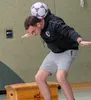 A man balancing a soccer ball on his head while standing on a wooden box. Anteprima dell’immagine prodotto