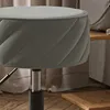 A close-up of a gray stool with a quilted pattern on its side. Produktbild-Vorschau