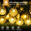 Close-up of solar string lights with water droplets, suggesting outdoor use in rain. Produktbild-Vorschau