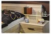A bedside table next to a bed, featuring a clock, books, and decorative bottles on a shelf. Anteprima dell’immagine prodotto