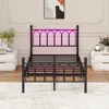 A black metal bed frame with pink LED lights in the headboard, set up in a bedroom with nightstands and a rug. Produktbild-Vorschau
