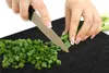Hands chopping green onions on a black cutting board. Náhľad obrázku produktu