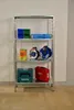A metal shelving unit filled with various tools and storage containers against a white brick wall. Produktbild-Vorschau