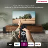 A person is holding a remote control in front of a TV, with various app logos at the bottom. Produktbild-Vorschau
