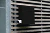 A black mailbox mounted on a wooden slat wall. Anteprima dell’immagine prodotto