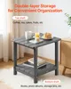 A gray plastic side table with two shelves, set up in a room with a white rug and a blurred background. Anteprima dell’immagine prodotto