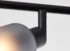 A close-up view of a black ceiling spotlight fixture, showing the connection between the main bar and a downward-facing arm, with a frosted glass shade partially visible. Produktbild-Vorschau