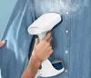A person is using a handheld garment steamer on a blue denim shirt. Produktbild-Vorschau