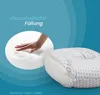 A hand pressing into a white foam material, with a pillow in the foreground. Produktbild-Vorschau
