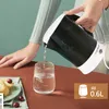 A person is pouring water from a black electric kettle into a glass. Produktbild-Vorschau