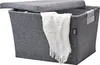 A grey felt storage basket with a lid and a white blanket draped over the side, set against a white background. Produktbild-Vorschau